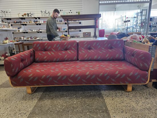 Sarkanīgs dīvāns ar koka elementiem