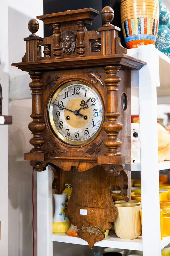 Uzvelkams tumšs mehāniskais retro sienas pulkstenis