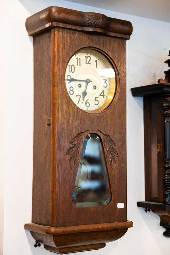 Uzvelkams mehāniskais sienas pulkstenis koka korpusā